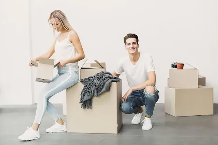 Молодая пара с коробками при переезде в светлую квартиру